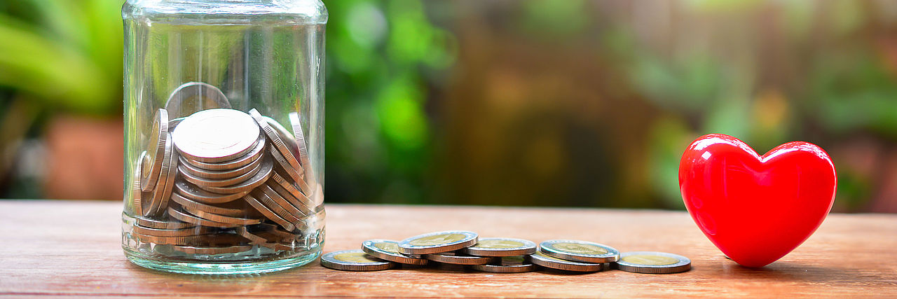 Spende mit Herz Spendendose, Geld liegt daneben und ein rotes Herz
