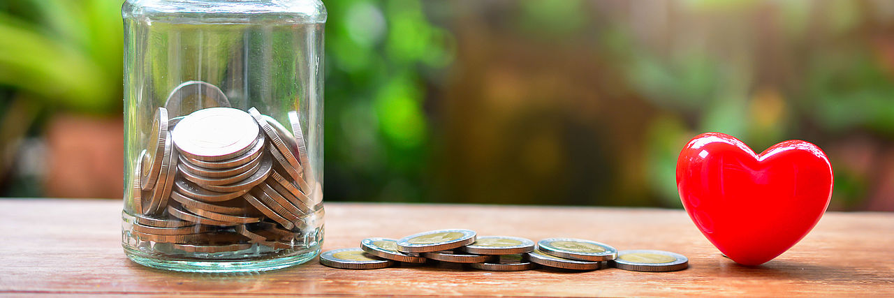 Spende mit Herz Spendendose, Geld liegt daneben und ein rotes Herz