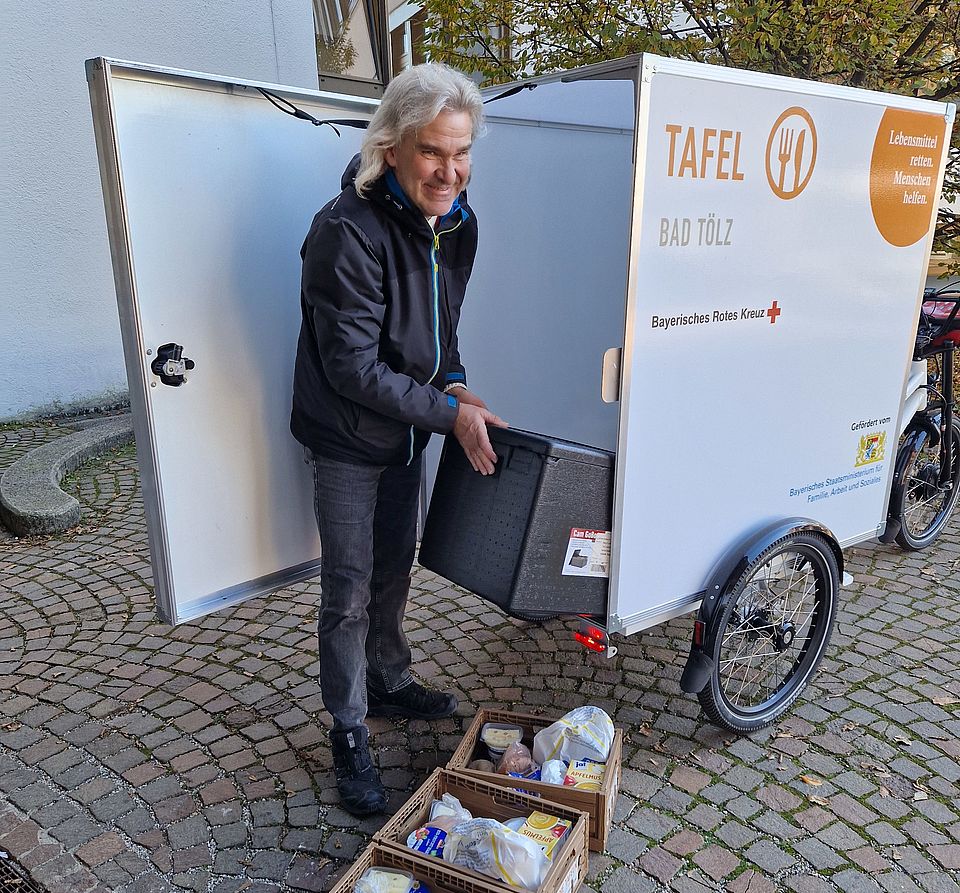 E-Lastenfahrrad der Tölzer Tafel - ein Ehrenamtlicher lädt Lebensmittel ein und fährt diese aus.