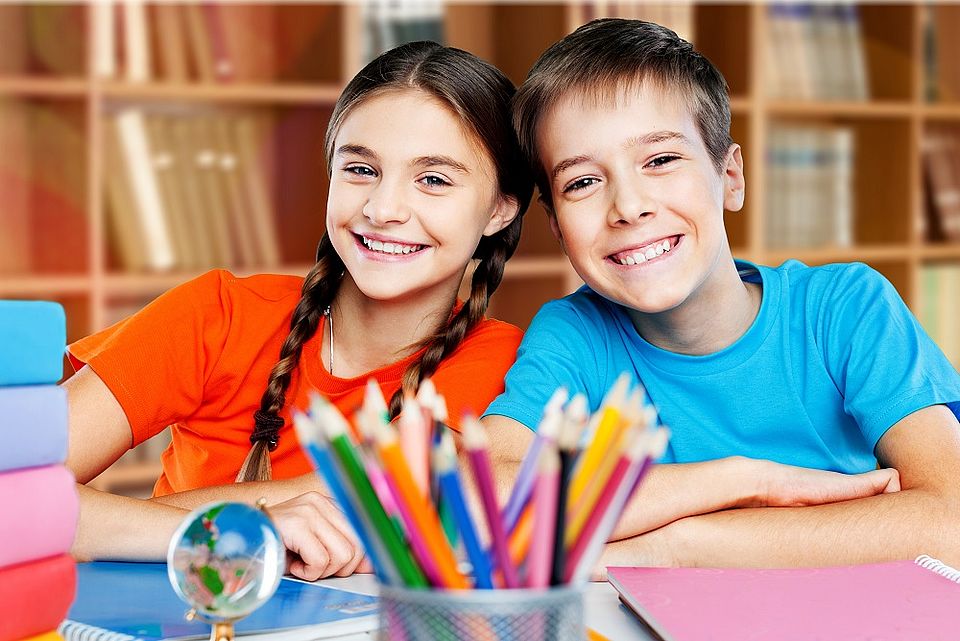 Zwei Schüler:innen sitzen am Tisch und haben Spaß am gemeinsamen Lernen Spaß
